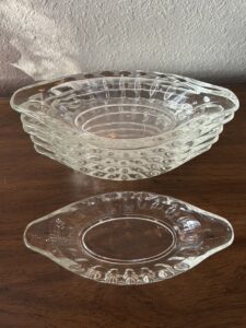 A stack of six clear vintage glass oval dishes with tab handles and a ribbed, thumbprint pattern, ready for ice cream or relishes.